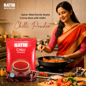 Indian woman in red saree cooking spicy curry in home kitchen using Hathi Chilli Powder for rich flavour and colour